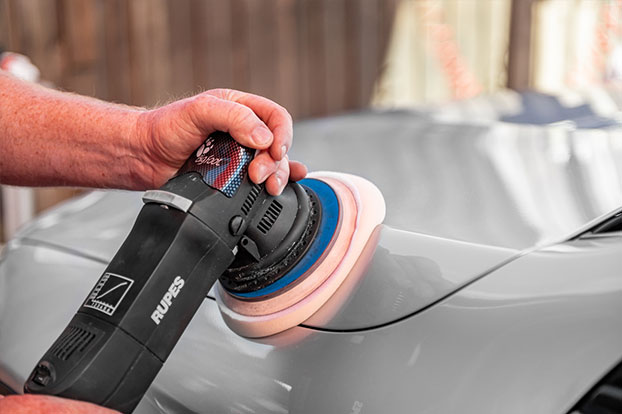 person buffing & polishing car exterior