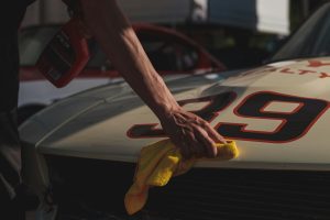 close up of a person wiping a white race car with a microfibre cloth
